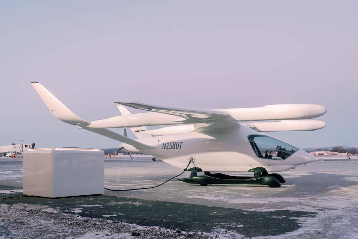 Side view of a white eVTOL plugged in and charging on the runway