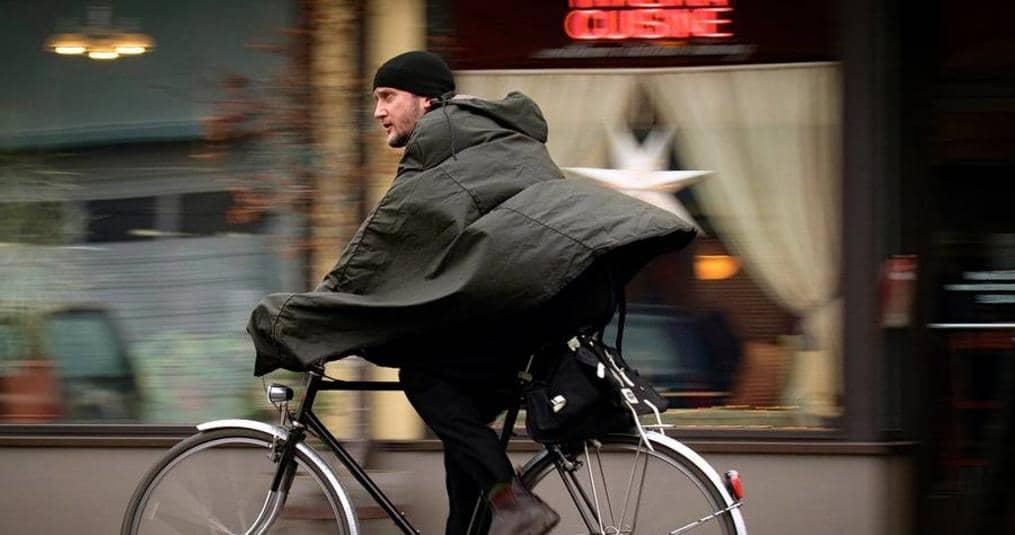 A cyclist wearing a rain cape in the wind. Loose clothes will create drag. CREDIT: www.clevercycles.com